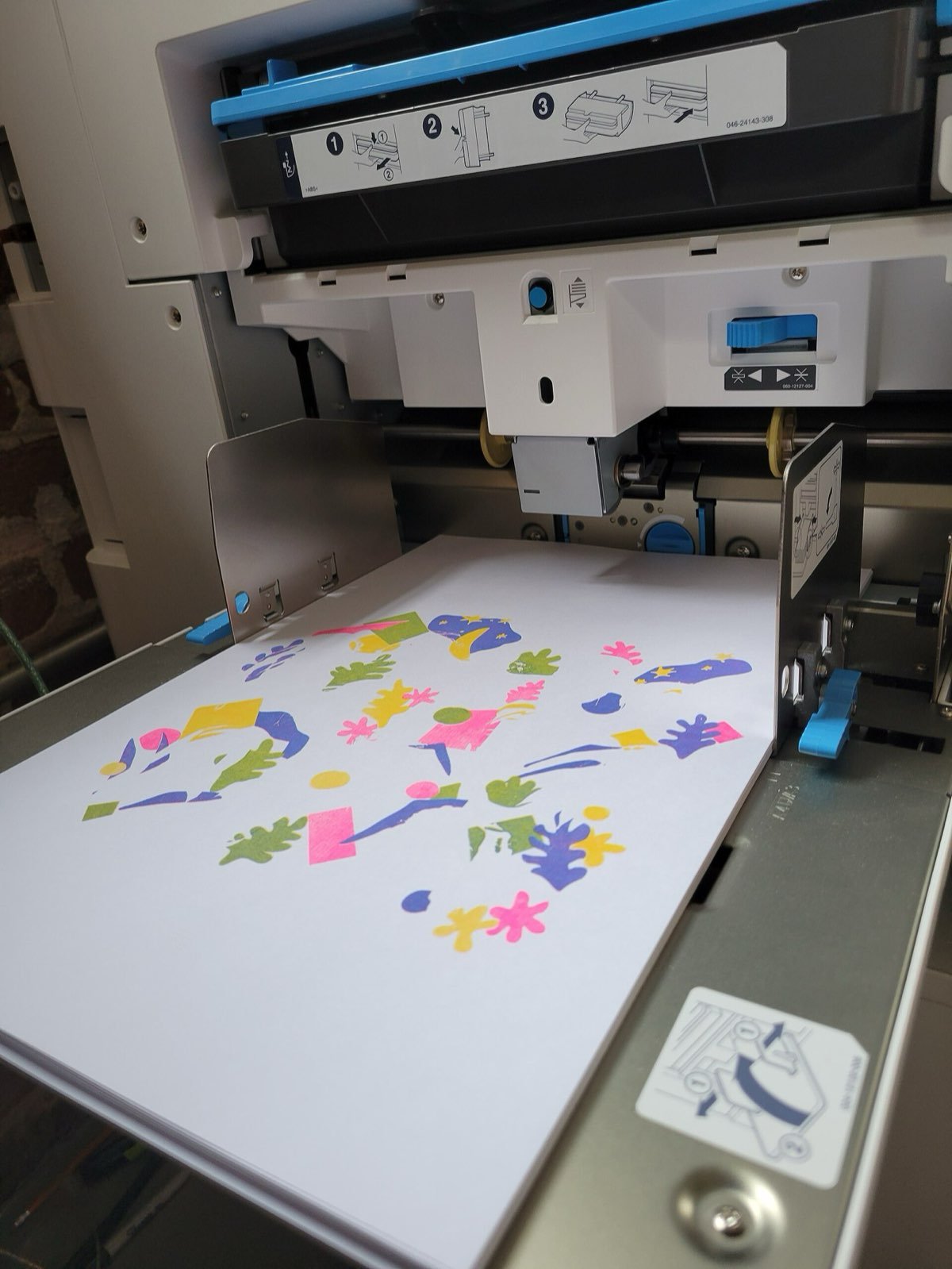 Un foglio appena uscito da una stampante risograph, con forme a colori.